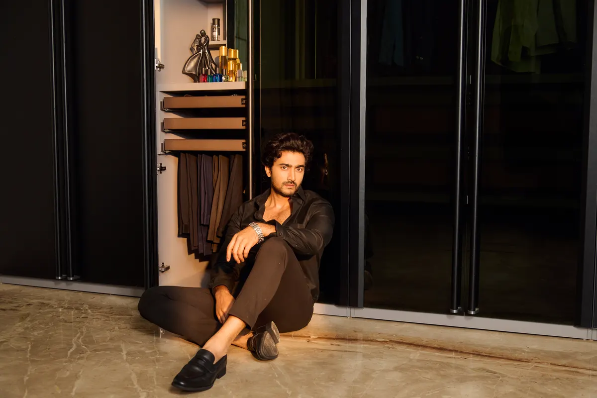 A walk-in wardrobe in dark glass with lit shelving, built by Orovell